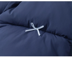 Detail of dark blue quilted jacket featuring a small light blue decorative bow accent
