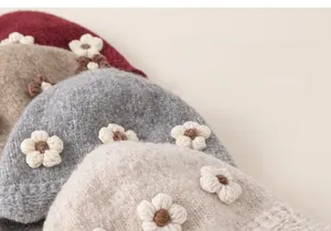 Close-up of winter knit hats with 3D floral accents in soft cream and khaki textures