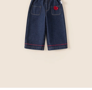 Detail of kids denim jeans showing red apple embroidery and decorative stitching