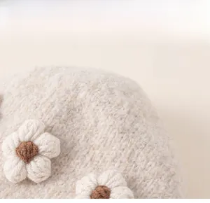 Detail of warm winter knit hat with 3D flower accent and coarse wool texture for girls