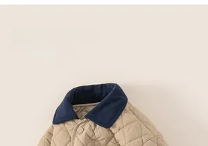 Detail of children quilted jacket showing navy blue contrast collar and beige diamond patterns
