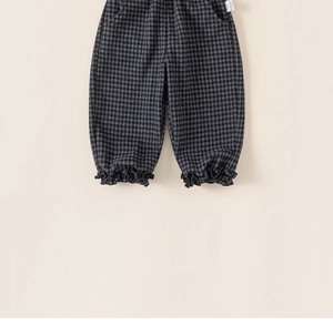 Détail de pantalon à carreaux pour enfants avec bords à volants et étiquette latérale