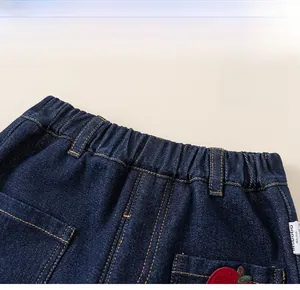 Detailed close-up of dark blue kids denim jeans featuring elastic waistband and embroidery
