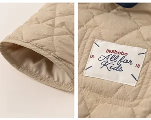 Detail of khaki quilted kids jacket showing diamond stitching and letter patch on sleeve