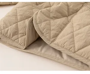 Detail of khaki quilted jacket featuring diamond stitching and curved hem for children