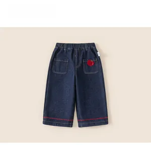 Detail view of navy blue kids denim trousers with apple embroidery and elastic waist