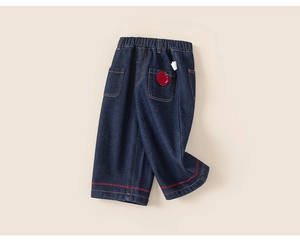 Detail of kids denim pants showing elastic waist and cute red apple embroidery on back pocket