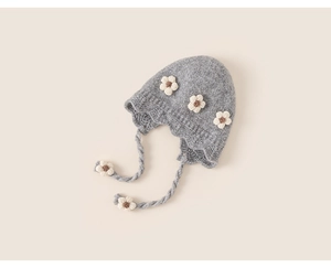 Close-up of grey knitted toddler hat with white 3D floral accents and earflap straps