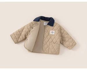 Detail of diamond quilted kids jacket with contrast navy corduroy collar and snap buttons