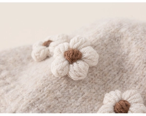 Close-up of soft beige knitted fabric with delicate handmade crochet flower details