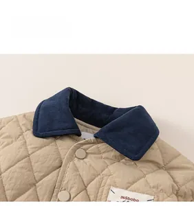 Detailed close-up of quilted beige jacket with navy corduroy collar and button snap