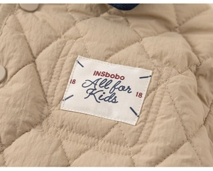 Detail of children's quilted jacket featuring brand label and snap button closure