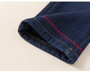 Close-up of kids denim jeans showing dark blue fabric with red polka dot embroidery