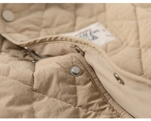 Detail of diamond quilted texture and silver metal snap buttons on children's padded jacket