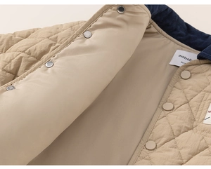 Detail of baby quilted jacket featuring navy corduroy collar and snap button closure