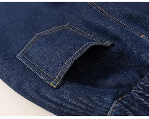 Detailed close-up of dark blue kids denim pants showing reinforced stitching and back pocket