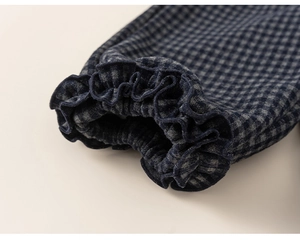 Détail de poignets élastiques à volants avec motif à carreaux bleus sur pantalon enfant