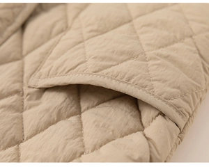 Detailed macro view of the beige quilted diamond stitching texture on children's winter jacket