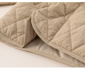 Close-up of diamond quilted texture and neat stitching on beige children's jacket hem