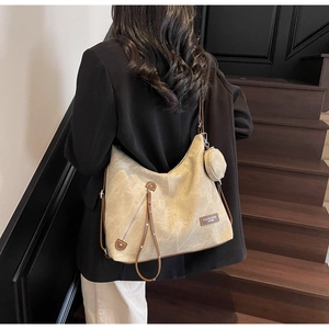 Detail of khaki canvas tote with brown leather trim and round coin purse accessory