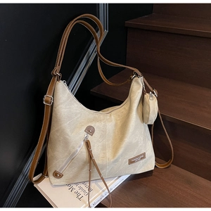 Detail of beige canvas tote bag with brown leather straps and small coin purse attachment