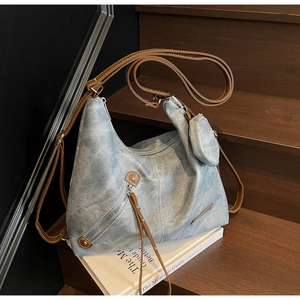 Detail view of light blue denim tote bag with leather straps and a mini round coin purse