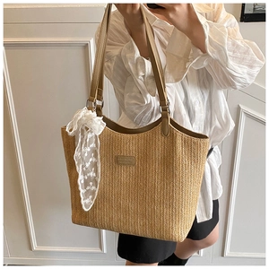 Detail shot of the large woven tote bag featuring a leather patch and white lace scarf