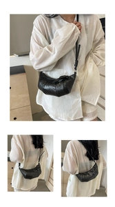 Détail du sac croissant noir avec bandoulière nouée et texture cuir ciré brillant