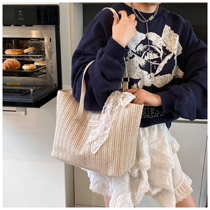Detailed woven straw tote bag texture with elegant lace scarf and white shoulder straps