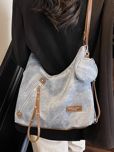 Light blue denim tote bag with brown leather straps shown from a side-view on a model