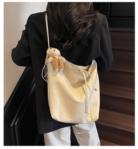 Detail of a large cream white PU leather hobo bag with a cute bear plush keychain