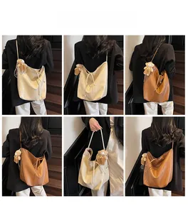 Detail view of large faux leather tote bag with drawstring closure and bear charm accessory