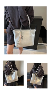 Detail view of silver tote bag featuring crinkled metallic texture and tassel pendant