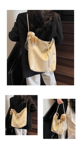 Detail view of large cream tote bag featuring textured faux leather and teddy bear charm