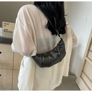 Détail du sac croissant noir avec nœuds décoratifs et texture en similicuir craquelé