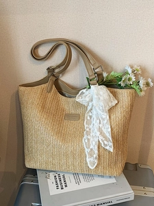 Large beige woven straw tote bag with brown faux leather handles and lace scarf detail