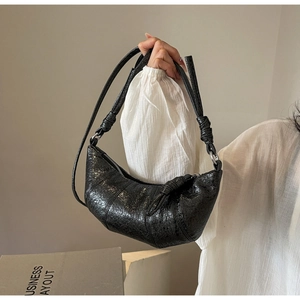 Vue détaillée du sac croissant en cuir PU noir brillant avec des boucles métalliques