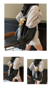 Detailed close-up of large soft leather black tote bag with drawstring and bear pendant
