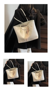 Detail of creamy white glossy tote bag featuring decorative woven tassel charms