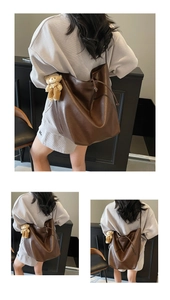 Detail of a large brown drawstring tote bag with soft leather texture and bear charm