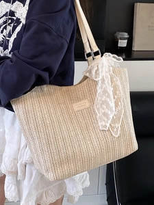 Straw woven tote bag with white lace scarf and leather straps in a home setting