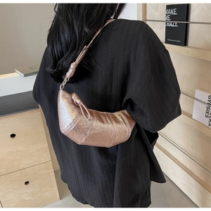 Détail du sac croissant doré rose métallisé avec texture plissée et bandoulière nouée