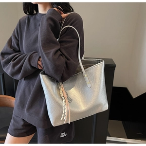 Detail of silver metallic tote bag featuring pleated texture and colorful tassel pendant
