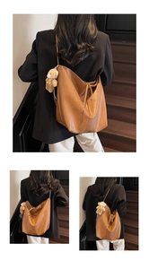 Detail of soft brown leather tote bag with a cute plush bear charm on wooden stairs