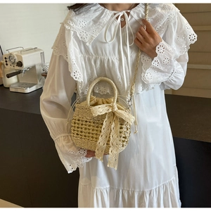 Détail du sac en paille tissé avec nœud en dentelle et doublure sur une robe blanche