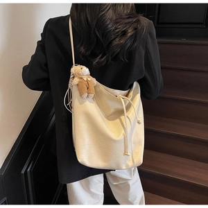 Detail of soft cream white tote bag with drawstring closure and cute bear pendant