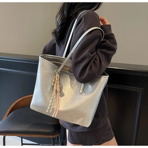 Silver tote bag with crinkled texture and braided tassel charm on shoulder strap