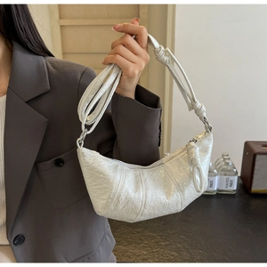 Détail du sac croissant blanc crème avec poignée nouée et texture en cuir verni plissé