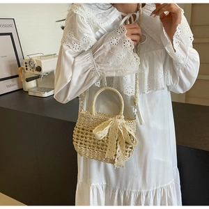 Détail du sac en paille beige tissé à la main avec nœud en dentelle et bandoulière