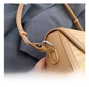 Détail de la bandoulière en cuir réglable avec boucle en métal argenté du sac en paille